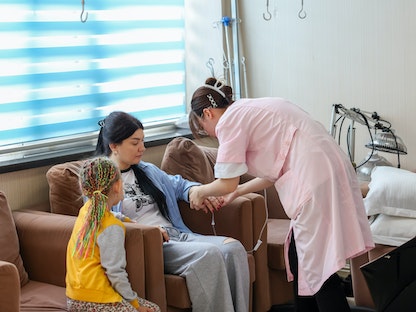 ممرضة تقدم علاجاً بالوريد لمريضة في مستشفى شمال شرق الصين. 28 يونيو 2023 - AFP