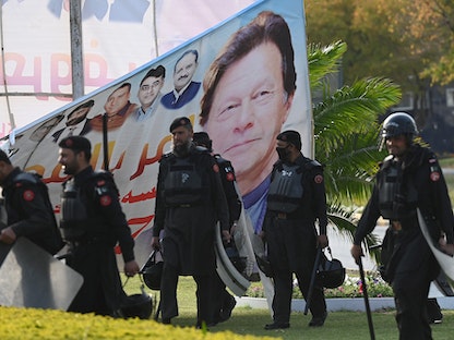 قوات الأمن الباكستانية أمام لافتة تحمل صورة رئيس الوزراء عمران خان بالقرب من مبنى البرلمان في إسلام أباد -  3 أبريل 2022 - AFP