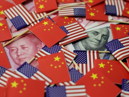 صورة توضيحية للعلمين الأميركي والصيني فوق عملات من الدولار واليوان - REUTERS