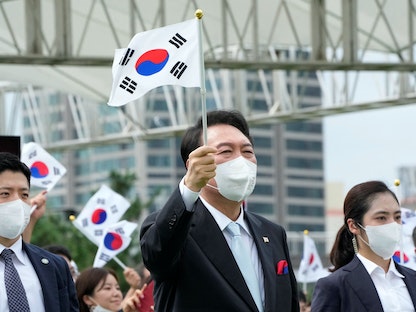 الرئيس الكوري الجنوبي يون سوك يول يلوّح بعلم بلاده في سول خلال احتفال بيوم التحرير من الاستعمار الياباني. 15 أغسطس 2022 - REUTERS