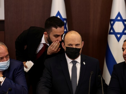 رئيس الوزراء الإسرائيلي نفتالي بينيت يستمع لأحد أعضاء فريق عمله خلال اجتماع وزاري - 28 نوفمبر 2021 - REUTERS