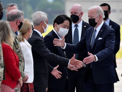 وزير الخارجية الياباني يوشيماسا هاياشي (وسط) وسفير واشنطن لدى اليابان رام إيمانويل يستقبلان الرئيس الأميركي جو بايدن لدى وصوله إلى قاعدة يوكوتا الجوية في فوسا بالعاصمة طوكيو. 22 مايو 2022 - AFP