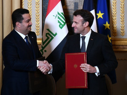 الرئيس الفرنسي إيمانويل ماكرون يصافح رئيس الوزراء العراقي محمد شياع السوداني عقب التوقيع على اتفاقية شراكة في باريس - 26 يناير 2023 - REUTERS