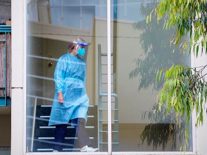 عاملة رعاية صحية تسير في مجمع كينجز بارك تاون هاوس المغلق خلال تفشي فيروس كورونا في مدينة ملبورن الأسترالية - 16 يونيو  2022 - REUTERS