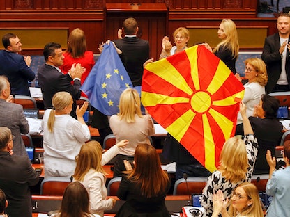 أعضاء في برلمان مقدونيا الشمالية يرفعون علم بلادهم وعلم الاتحاد الأوروبي خلال جلسة للبرلمان. 16 يوليو 2022 - REUTERS