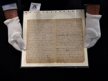 بائع في مزاد باريس يحمل رسالة فان غوخ وبول غوغان - AFP
