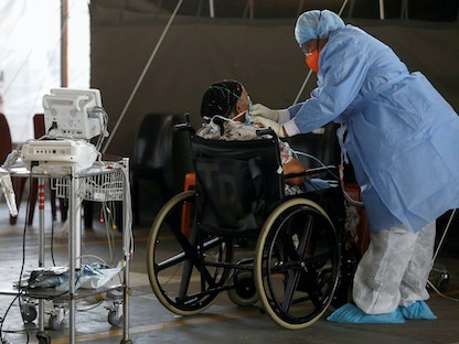 عامل رعاية صحية يراقب صحة مريض في جناح مؤقت تم إنشاؤه أثناء تفشي مرض فيروس كورونا في مستشفى ستيف بيكو الأكاديمي في بريتوريا بجنوب إفريقيا  - REUTERS