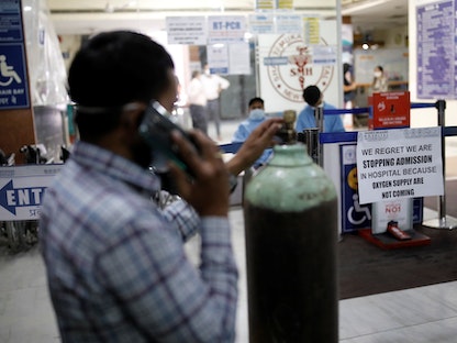 رجل يقف وبجواره أنبوبة أكسجين وسط تفشي فيروس كورونا في الهند - REUTERS