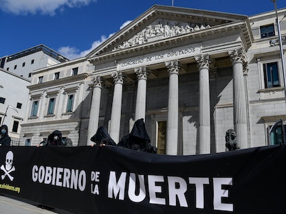 متظاهرون يحملون لافتة كتب عليها "حكومة الموت" خلال مظاهرة ضد قانون يشرع الموت الرحيم في مدريد، 18 مارس 2021 - AFP