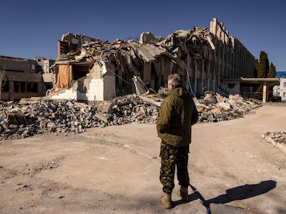 أحد أفراد قوات الدفاع الأوكرانية يقف أمام منزل مدمر في مدينة جيتو-مير شمال أوكرانيا - 23 مارس 2022 - AFP