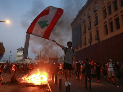 متظاهر يحمل العلم اللبناني خلال مظاهرة بالقرب من البرلمان، حيث يحيي لبنان الذكرى الأولى للانفجار في بيروت، لبنان- 4 أغسطس 2021 - REUTERS