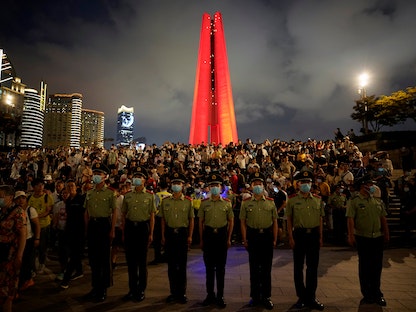 قوات أمنية تراقب بينما يتجمع الناس لمشاهدة عرض ضوئي للاحتفال بالذكرى المئوية لتأسيس الحزب الشيوعي الصيني في شنغهاي - 30 يونيو 2021 - REUTERS