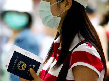 مسافرة صينية تحمل جواز سفرها عند نقطة تفتيش حدودية - REUTERS