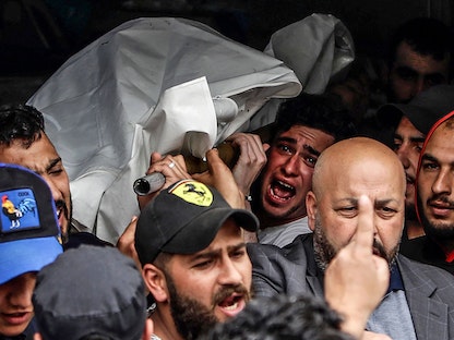 مشيعون يحملون جثة شخص ممن غرقوا عندما انقلب قاربهم قبالة سواحل طرابلس في مشرحة مستشفى بمدينة طرابلس شمال لبنان- في 24 أبريل 2022 - AFP