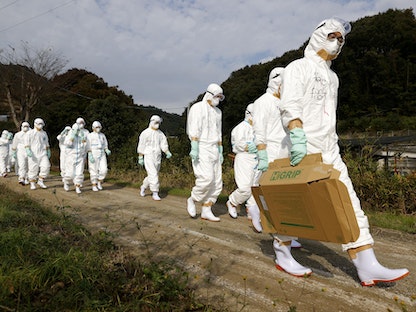 مسؤولون صحيون في بزّات واقية يتوجهون إلى مزرعة دواجن غربي اليابان يشتبه بتفشي المرض فيها - 8 نوفمبر 2021 - REUTERS