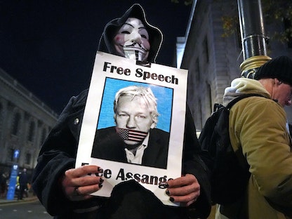 متظاهر يحمل صورة لمؤسس ويكيليكس جوليان أسانج في تجمع بميدان ترافالجار في لندن، 5 نوفمبر 2020 - AFP