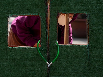 أحد السكان ينظر إلى الخارج من خلال حاجز في منطقة سكنية أثناء الإغلاق وسط جائحة كورونا في شنغهاي، الصين، في 3 مايو 2022 - REUTERS
