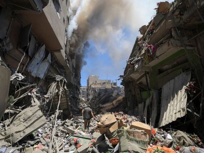 دخان يتصاعد بينما يتفقد فلسطيني موقعاً تعرض لغارات إسرائيلية على المباني في سوق البلدة القديمة بمدينة غزة. 9 يوليو 2025 - REUTERS