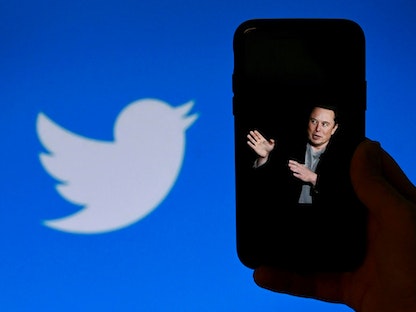 هاتف يعرض صورة إيلون ماسك وفي الخلفية شعار "تويتر". 4 أكتوبر 2022 - AFP