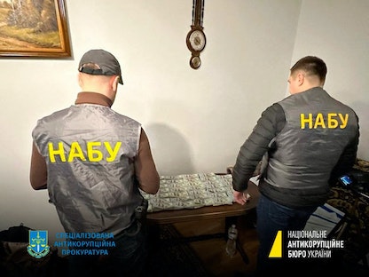 شرطة مكافحة الفساد الأوكرانية بجانب أموال تم حجزها خلال مداهمات لمنازل ومكاتب مسؤولين- 23 يناير 2023 - AFP