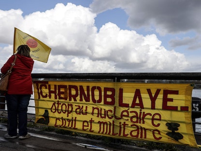 متظاهرة تقف بجانب لافتة كتب عليها "تشيرنوبلاي.. أوقفوا النووي المدني والعسكري" خلال مظاهرة مناهضة للأسلحة النووية في بوردو جنوب غربي فرنسا. 13 مارس 2022 - AFP