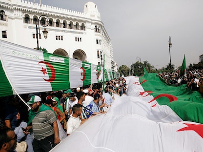 متظاهرون في الجزائر العاصمة يرفعون العلم الجزائري - REUTERS 