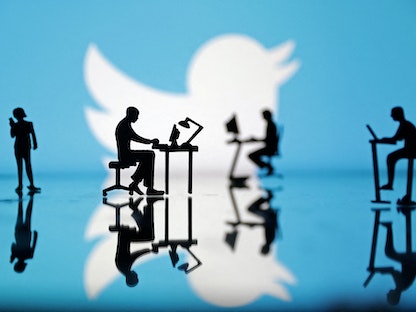 رسم توضيحي لشعار تويتر في خلفية أشخاص يستخدمون الحاسب الآلي والموبايل. 24 يوليو 2022 - REUTERS