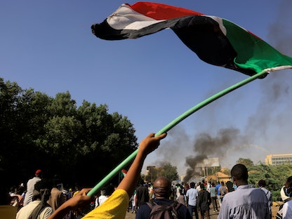 متظاهر في العاصمة الخرطوم يرفع علم السودان - 9 يناير 2022 - REUTERS