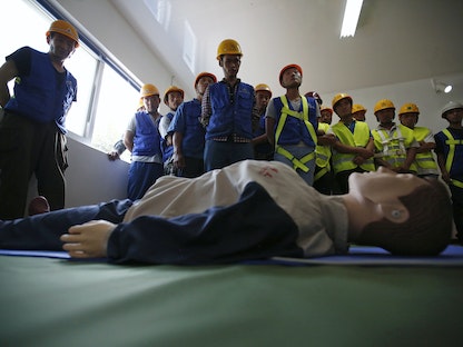 عمال بناء يخضعون لتدريبب حول الإسعافات الأولية في حالات الصدمة الكهربائية، في بكين- 5 سبتمبر 2014 - REUTERS