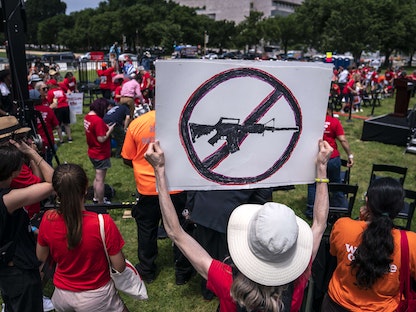 مشارك في مسيرة ضد العنف المسلح يحمل لافتة تطالب بحظر الأسلحة الهجومية، واشنطن- 8 يونيو 2022 - AFP