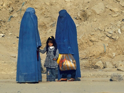 سيدتان وطفلة ينتظرن وسيلة نقل على طريق في كابول، أفغانستان- 5 نوفمبر 2012. - REUTERS