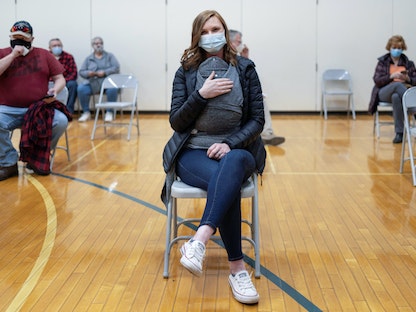 امرأة مع رضيعها تنتظر دورها لأخذ لقاح مضاد لفيروس كورونا في بنسلفينيا - الولايات المتحدة - 7 مارس 2021  - REUTERS