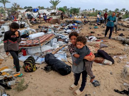 طفلة فلسطينية تحمل شقيقها الصغير في أعقاب غارة إسرائيلية على خيام النازحين بخان يونس جنوبي قطاع غزة. 18 مايو 2025 - REUTERS