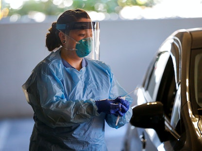 ممرضة تجري مسحة أنف لمريض في سيارته في مركز فحص من السيارة في واشنطن. 9 مارس 2020  - REUTERS