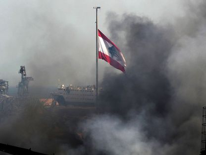 علم لبنان يرفرف وسط تصاعد الدخان من حريق في ميناء بيروت، 11 سبتمبر 2020 - AFP