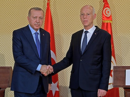 الرئيس التونسي قيس سعيد يصافح نظيره التركي رجب طيب أردوغان خلال مؤتمر صحافي مشترك في القصر الرئاسي بقرطاج شرقي العاصمة تونس - 25 ديسمبر 2019 - AFP