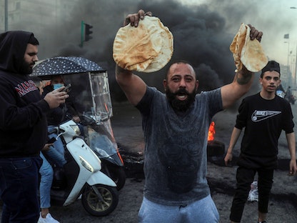 متظاهر يحمل خبزاً مدعوماً من الحكومة خلال احتجاجات في بيروت، 2 مارس 2021 - Bloomberg