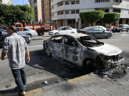 رجل يسير بجوار سيارة محترقة بعد اشتباكات طرابلس، ليبيا 28 أغسطس 2022 - REUTERS
