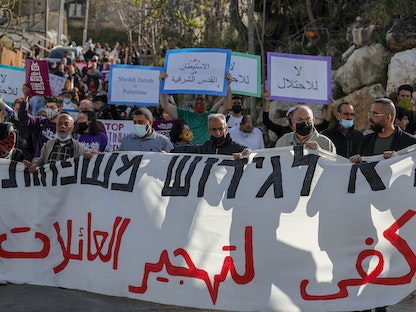 متظاهرون فلسطينيون يرفعون لافتات ضد عمليات الاستيطان الإسرائيلي في حي الشيخ جراح بالقدس - AFP