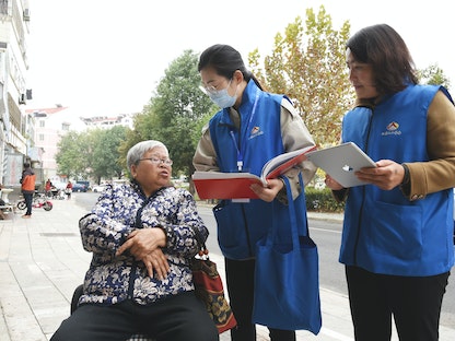موظفتان في التعداد السكاني تجمعان معلومات من امرأة في مدينة يانيونغانغ في الصين 1 نوفمبر 2020 - AFP