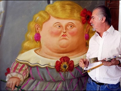 الفنان الراحل فرناندو بوتيرو إلى جانب إحدى لوحاته.  - fernandobotero.com