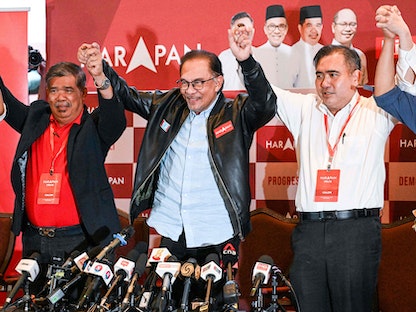 زعيم المعارضة الماليزية أنور إبراهيم (وسط الصورة) يحتفي في نهاية مؤتمر صحفي في كوالالمبور في 20 نوفمبر 2022. - AFP