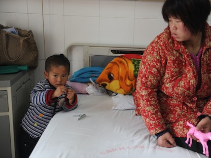 صينية ترافق طفلها المصاب بالتهاب الكبد الوبائي سي في مستشفى بمدينة خفي عاصمة مقاطعة آنهوي شرقي الصين. 28 نوفمبر 2011 - AFP