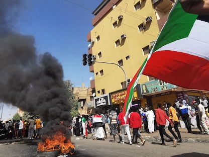 متظاهرون يجملون أعلام السودان خلال احتجاجات تطالب بسلطة مدنية - 9 يناير 2022  - AFP