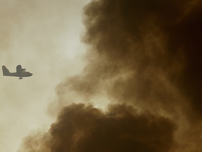 طائرة إطفاء وسط أعمدة الدخان أثناء مشاركتها في عمليات إخماد حرائق غربي أثينا في اليونان. 20 يوليو 2023 - REUTERS