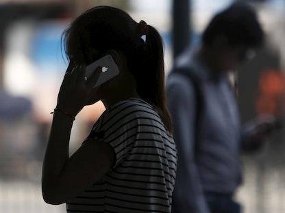 سيدة تجري مكالمة هاتفية عبر هاتف "آيفون" في أحد شوارع شنغهاي - REUTERS