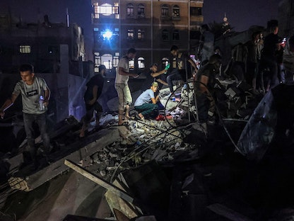 فلسطينيون يبحثون عن جرحى وسط أنقاض مبنى في أعقاب غارة إسرائيلية على رفح جنوب قطاع غزة - 6 أغسطس 2022 - AFP