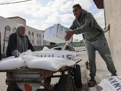 فلسطينيون يحملون مساعدات غذائية من وكالة "الأونروا" بمخيم رفح للاجئين جنوب قطاع غزة. 22 يناير 2023 - AFP