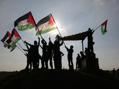 يلوحون بعلم فلسطين بالقرب من الحدود بين إسرائيل وقطاع غزة. - AFP