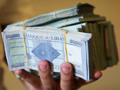 تاجر صرافة يعرض أوراقاً بالليرة اللبنانية في متجره بالعاصمة بيروت- 11 مايو 2021 - REUTERS